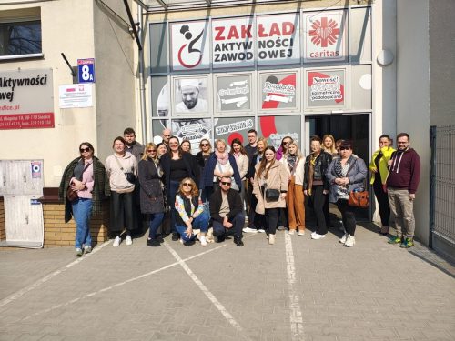 Grupowe zdjęcie przed wejściem do budynku.