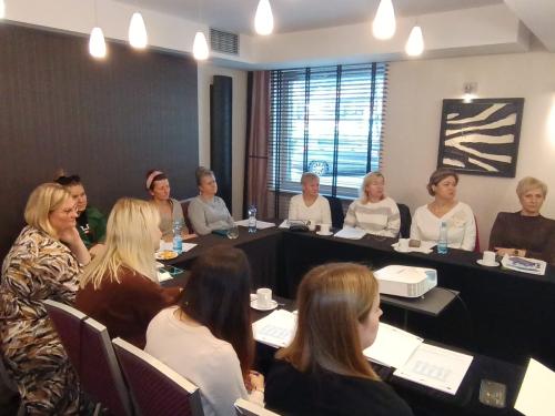 szkolenie w sprawie Nowelizacji ustawy o pomocy społecznej dzień pierwszy 11 uczestniczek skupionych na prelekcji nowoczesny wystrój małej sali dominuje czerń i biel z sufitu zwisają liczne żyrandole