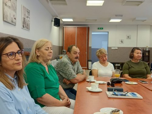 5 osób siedzi na rogu łączonych stołów.