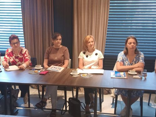 Podłużny stół przy którym siedzą 4 kobiety i patrzą w jednym kierunku.
