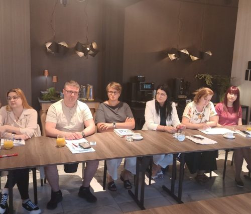 Podłużny stół przy którym siedzi 6 osób.