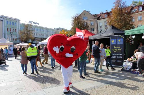maskotka targów czyli duże czerwone serducho na biłych nogach macha do obiektywu uśiechając się przy tym