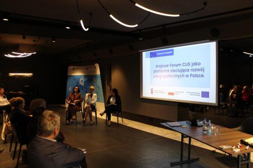 Konferencja ,,Kierunki rozwoju usług społecznych i procesu deinstytucjonalizacji w województwie podlaskim” na telebimie tytuł Krajowe forum Centrum Usług Społecznych jako platforma sieciująca rozwój usług społecznych w Polsce, poniżej do prawej Anna Ostasz – Przewodnicząca Zarządu Krajowego Forum Centrum Usług Społecznych, Katarzyna Żukowska-Koc – Dyrektor Centrum Usług Społecznych w Łapach oraz Izabela Wasielewska – Dyrektor Centrum Usług Społecznych w Stawiskach