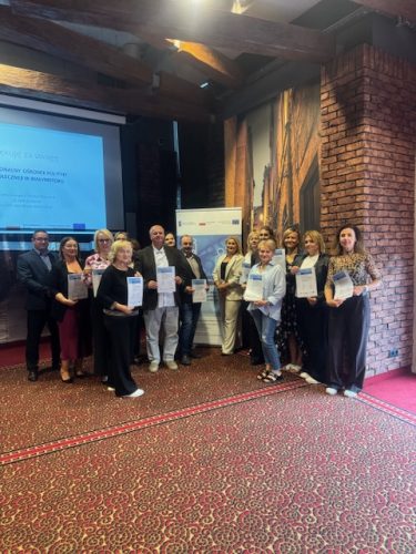 Wszyscy uczestnicy szkolenia specjalistycznego dla pracowników i kandydatów na pracowników centrum usług społecznych prezentują certyfikaty ukończenia