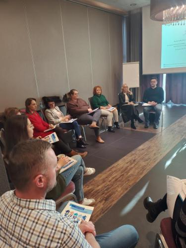 Relacja z superwizji pracy socjalnej uczestnicy siedzą w półkolu przed telebimem
