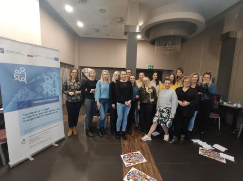Relacja z superwizji pracy socjalnej uczestnicy na zdjęciu grupowym z lewej plakat promujący Projekt „Koordynacja działań w zakresie polityki społecznej w województwie podlaskim”
