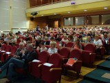 Liczna publiczność siedzi w kilku rzędach na sali wykładowej.