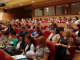 Liczna publiczność siedzi na sali wykładowej.