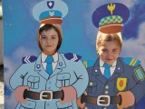 Dwie dziewczynki za fotościanką która przedstawia dwóch policjantów.