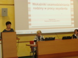 Trzy kobiety prowadzące seminarium, jedna przemawia na mównicy. W tle prezentacja multimedialna.