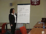 Kobieta stoi przy tablicy z narysowanym diagramem.