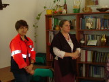 Dwie kobiety stoją obok siebie. Jedna z nich jest w czerwonej kurtce ratownika z odblaskami.