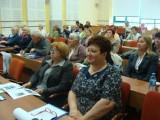 Grupa osób siedzi w kilku rzędach i patrzy w jednym kierunku.
