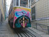Stary tramwaj pomalowany różnymi kolorami w stylu graffiti. Tramwaj znajduje się w wąskiej uliczce.