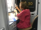 Kobieta siedzi przy biurku w nietypowo wyposażonym samochodzie dostawczym i pobiera próbkę z butelki.