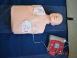 Fantom z przyklejonym defibrylatorem AED.