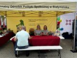 Dwie uśmiechnięte blondynki prezentują stoisko Regionalnego Ośrodka Polityki Społecznej w Białymstoku na dożynkach