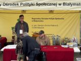 Dwóch pracowników Regionalnego Ośrodka Polityki Społecznej w Białymstoku prezentuje stoisko