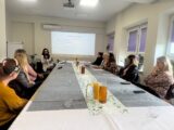 kolejne ujęcie prezentacji na temat funkcjonowania cus podczas wizyty studyjnej do Centrum Usług Społecznych w Stawiskach prowadząca to brunetka