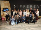 Grupowe zdjęcie na tle dużego banera z napisem DIFFEREN. Osoby w pierwszym rzędzie klęczą.