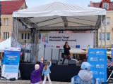 Scena na której śpiewa piosenkarka. W tle baner z napisem Podlaskie Targi Ekonomii Społecznej.